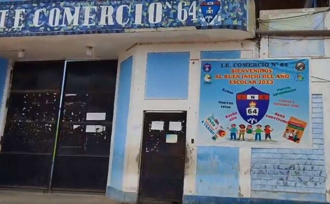 Fachada principal del colegio con el letrero I.E. Comercio N.º 64 y un banner de bienvenida al año escolar.