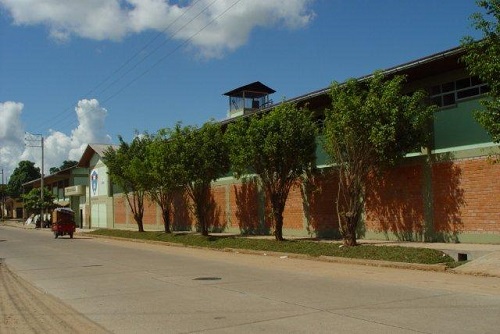 Vista exterior del local escolar desde la calle, con árboles a lo largo del cerco perimétrico.